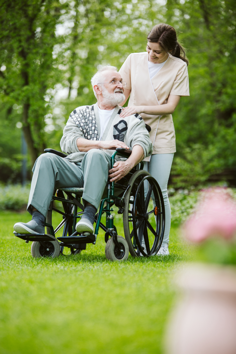 Älterer Mann im Rollstuhl im Garten eines professionellen Pflegeheims